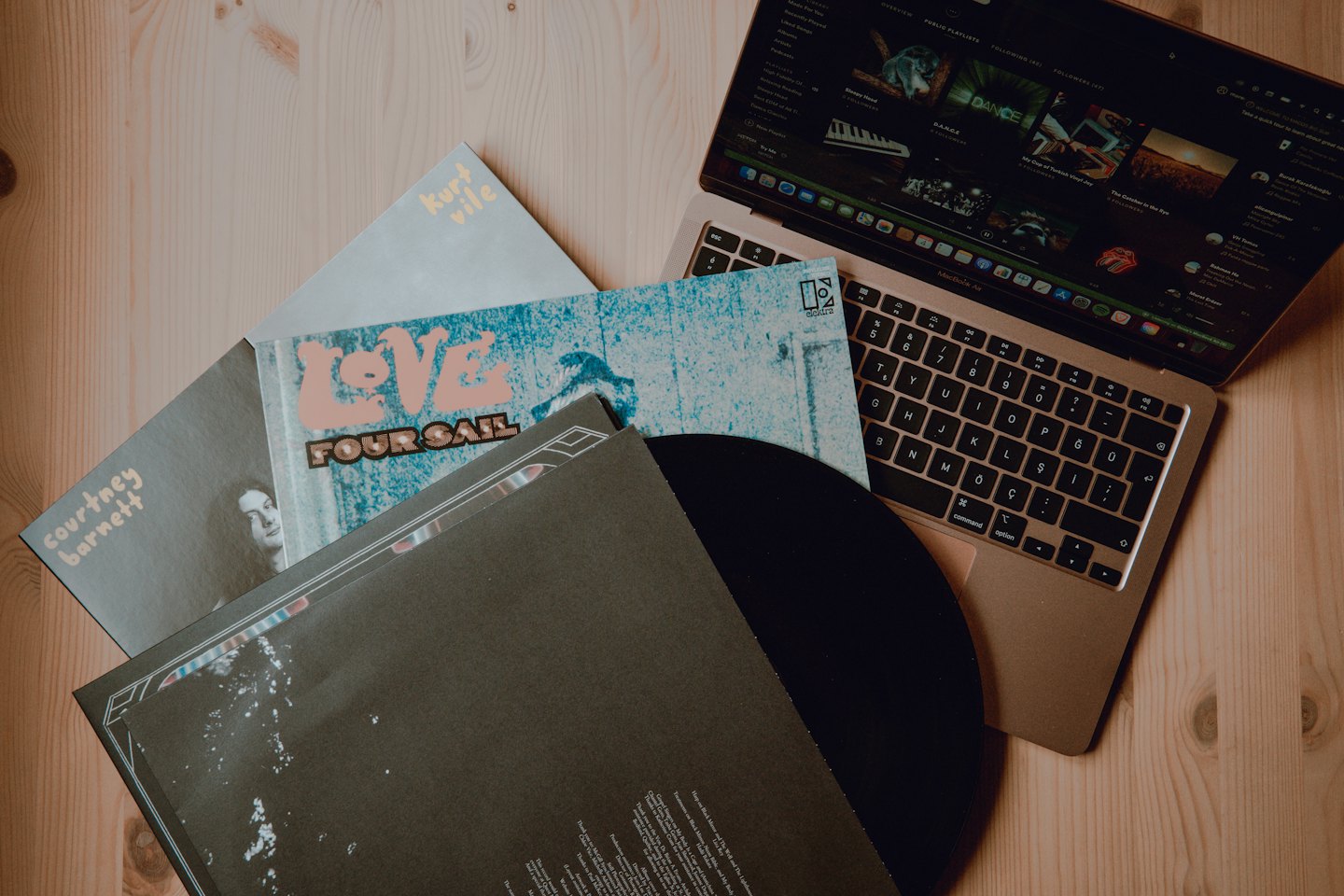 Dischi in vinile e MacBook su una scrivania di legno.