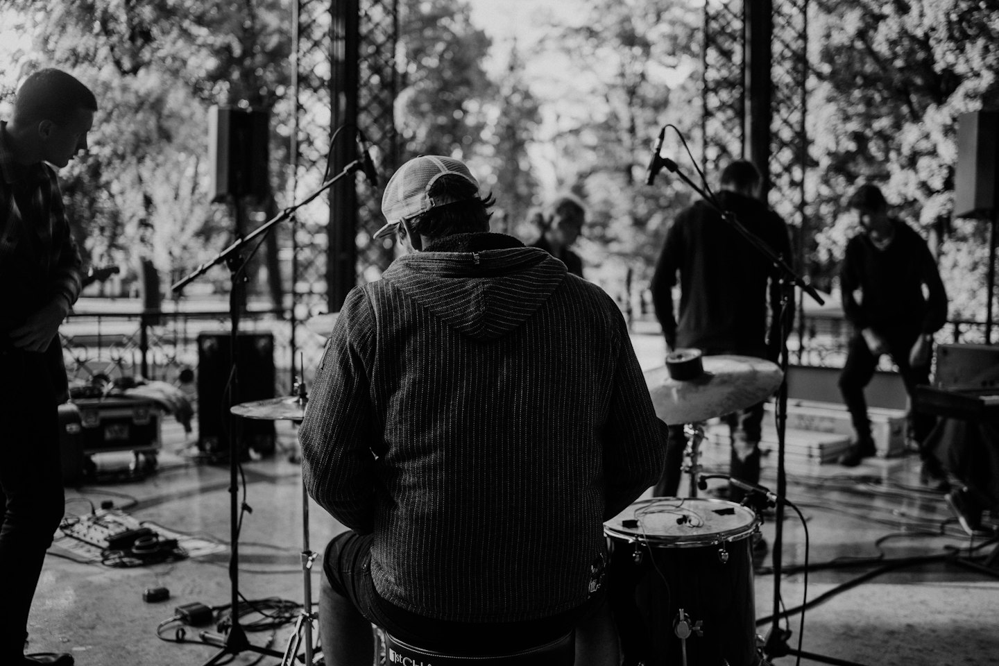 Musicisti preparano gli strumenti su un palco di legno all'aperto.