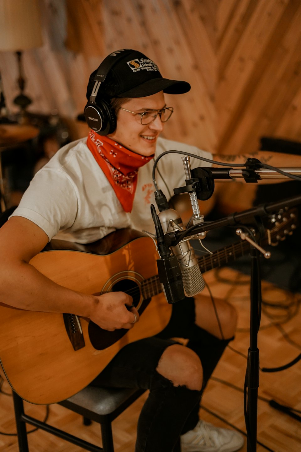 Uomo con cuffie suona la chitarra in uno studio di registrazione.